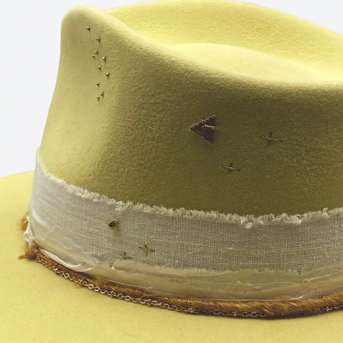 A lemon felt fedora hat with linen trimmings and gold details by Valeria Andino