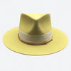 A lemon felt fedora hat with linen trimmings and gold details by Valeria Andino