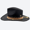 Side view of a Valeria Andino Handmade Straw Hat, its Classic cowboy shape in black with hand dyed silk trimmings, stones and gold jewelry